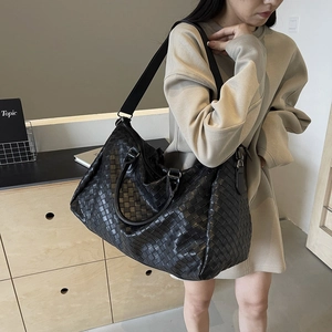 Large black woven leather tote bag with shoulder strap for casual travel and fashion use