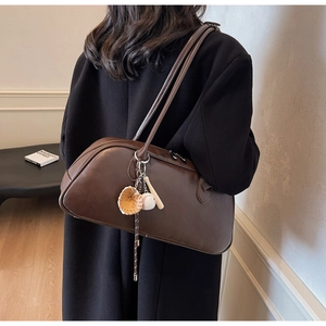 Detail of dark brown baguette bag with a unique baseball bat and glove charm accessory