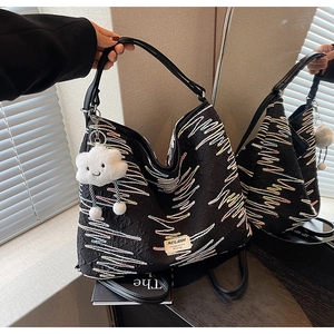 Detail of black textured hobo bag with colorful wavy embroidery and plush cloud charm