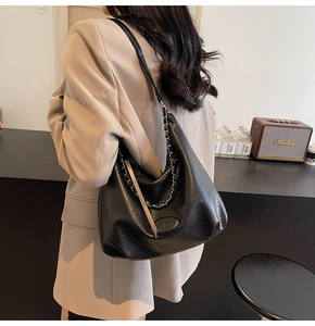 Dettaglio della borsa tote in pelle nera martellata con catena argento e tracolla larga