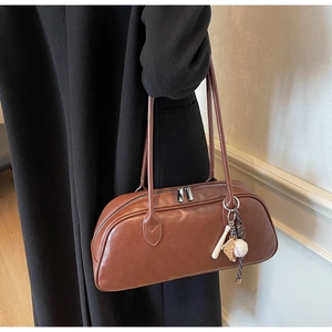 Close-up of brown leather bag with silver zippers and a sports themed keychain