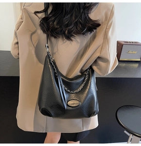 Dettaglio borsa hobo in pelle litchi nera con catena d'argento e placca ovale elegante