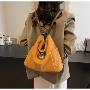 Detailed view of ginger yellow tote bag with round metal logo and brown leather straps
