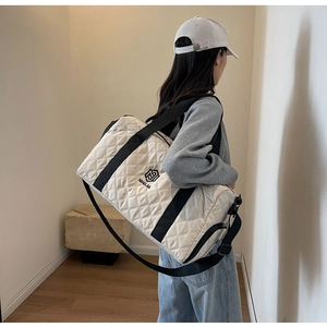 Grande borsa da viaggio trapuntata bianca indossata da una modella in un interno