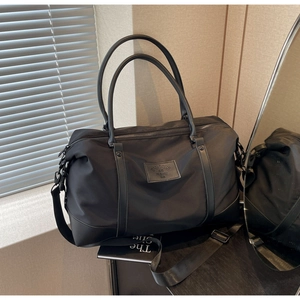Detail of high-capacity black nylon travel bag with premium leather handles and brand patch