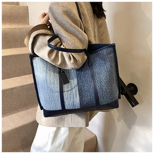 Detail of blue denim patchwork tote bag showing leather trim and texture on shoulder
