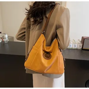 Detail of ginger yellow tote bag with silver M logo and dark brown shoulder strap