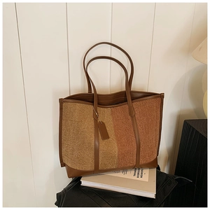 Detailed view of a two-tone tweed tote bag with leather trim in a cozy studio setting