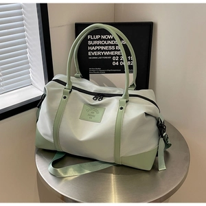 Macro detail of mint green travel bag featuring thick dual handles and brand logo patch