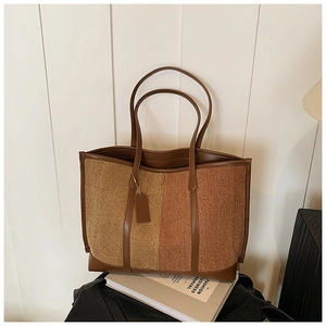 Detail of a large brown patchwork tote bag in textured tweed and premium leather