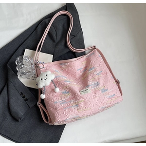 Detail of pink quilted tote bag with wave embroidery and white cloud plush pendant