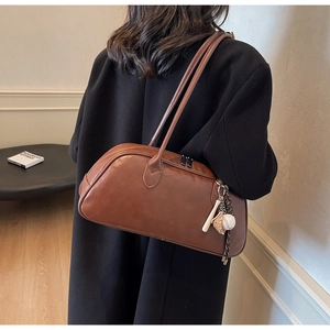 Detail view of brown faux leather shoulder bag with creative baseball metal charms