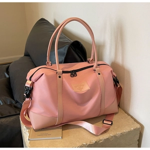 Pink waterproof travel bag showing reinforced leather handles and high-density fabric texture