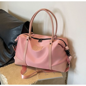 Detailed shot of a pink nylon travel bag with brand leather patch and black metal zippers