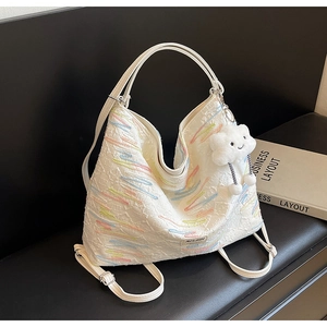 Detail of white embroidered hobo bag with colorful stitching and cloud plush keychain