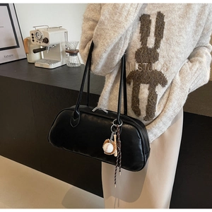 Close-up of black leather underarm bag with baseball charms and silver metal zipper