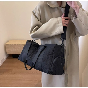 Dettaglio della borsa da viaggio trapuntata nera con tracolla regolabile e logo ricamato