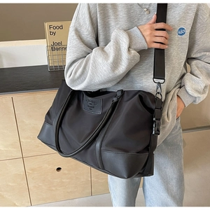 Detail of the large black nylon travel bag featuring leather handles and adjustable strap