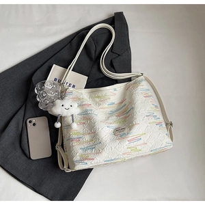 Detail of white tote bag with diamond stitching, wave embroidery, and cloud charm