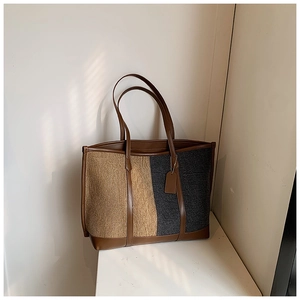 Detail of contrast color tote bag featuring woven fabric and brown leather textures