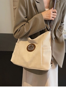 Chic cream tote bag with brown leather straps and metal M detail, worn by a model