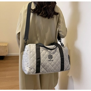 Dettaglio della borsa da viaggio trapuntata con texture grigia e logo del marchio