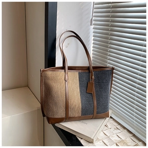 Close-up of contrast stitching and texture on a large capacity tote bag with leather straps
