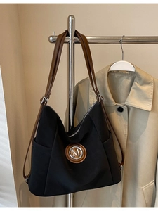 Retro black nylon tote bag with brown leather straps and metal M logo on trench coat
