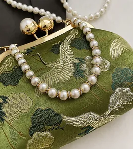 Detailed embroidery of cranes on olive green satin with elegant pearl handle
