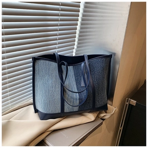 Close-up of a blue denim patchwork tote bag with contrast stitching on a window sill