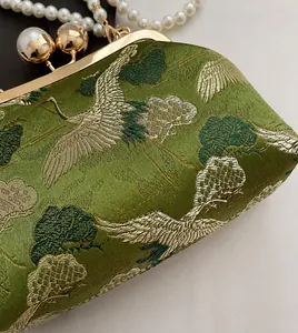 Detail of green oriental embroidery with crane and pine patterns on a satin evening clutch