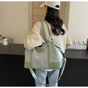 Rear view of a model carrying the mint green large capacity travel bag in a modern room