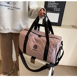 Dettaglio della borsa da viaggio trapuntata rosa su valigia bianca con tracolle nere