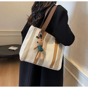 Detailed side view of large striped canvas tote bag with a cute plush bunny pendant