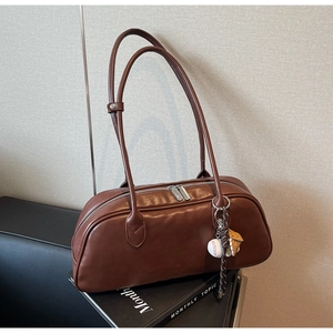 Detail of matte brown faux leather shoulder bag with silver zippers and baseball charm