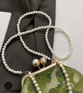 Detail of green satin embroidery bag with golden frame clasp and large pearl accents