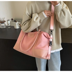 Detailed shot of pink nylon travel bag featuring adjustable strap and leather logo patch