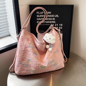 Pink jacquard tote bag with wavy embroidery and cloud charm on a stylish metal table