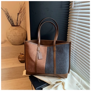 Detail of color-block tote bag featuring brown tweed and dark grey fabric with leather trim