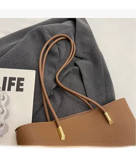 Detail of the brown lychee grain leather tote bag with durable handles and gold hardware