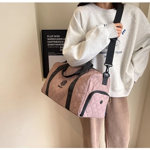 Borsa da viaggio trapuntata rosa con motivo a rombi e tracolla regolabile indossata a spalla