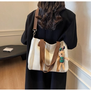 Detailed shot of striped canvas tote with adjustable strap and cute bunny pendant charm