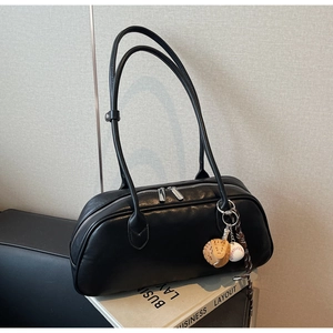Detail of black PU leather boston bag featuring double zippers and a baseball charm
