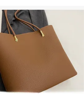 Detailed close-up of brown lychee grain PU leather shoulder bag with gold metal hardware