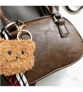 Detail of vintage brown faux leather handbag showing lychee texture and plush bear charm