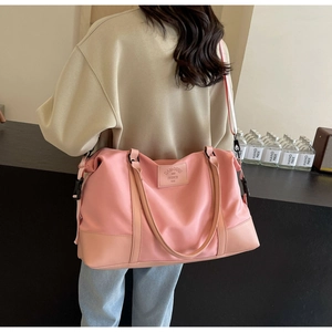 Close-up of pink nylon travel bag with crossbody strap and leather base detailing