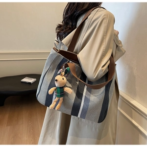 Detail of striped canvas tote bag with brown shoulder strap and cute bunny plush charm