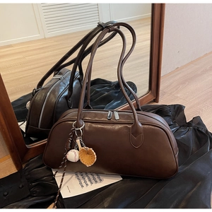Detail of brown vintage baguette bag featuring dual zippers and a unique baseball charm