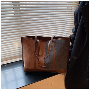 Close-up of contrast color tote bag featuring brown leather straps and felt texture