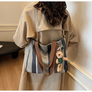Detail of striped canvas tote bag with adjustable brown straps and a cute plush bunny charm